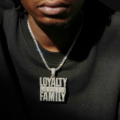 Black male wearing white gold tennis chain with an iced out pendant that reads loyalty makes you family. 